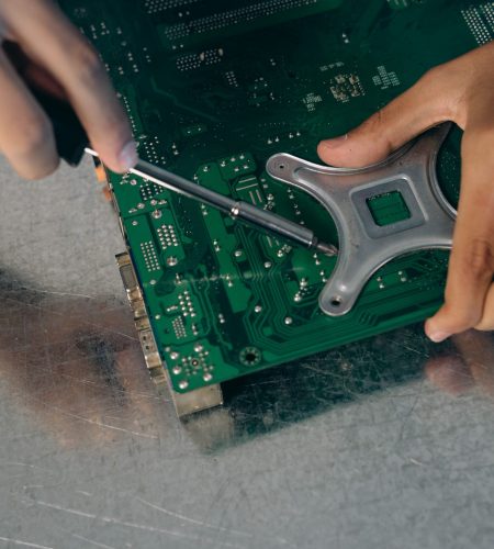 Detailed view of an engineer assembling a circuit board with a screwdriver.