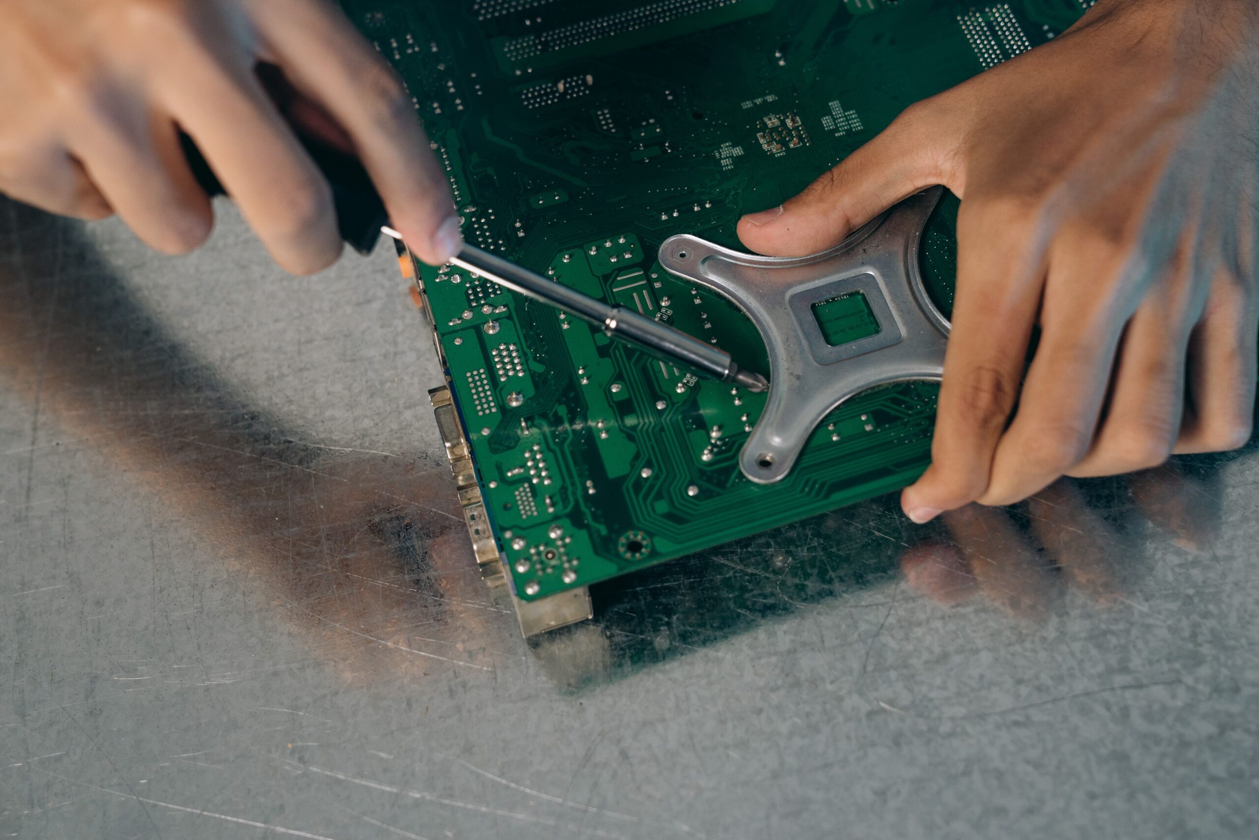 Detailed view of an engineer assembling a circuit board with a screwdriver.